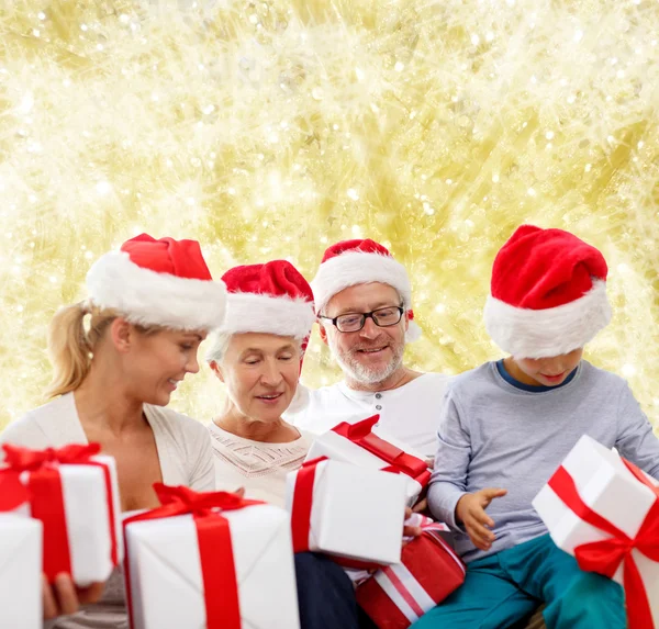 Happy family in santa helper hats with gift boxes — Stock Photo, Image