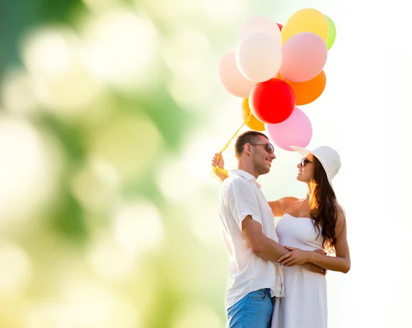 Casal sorridente com balões de ar ao ar livre — Fotografia de Stock