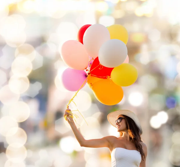 Gülümseyen güneş gözlüğü balonlarla genç kadın — Stok fotoğraf