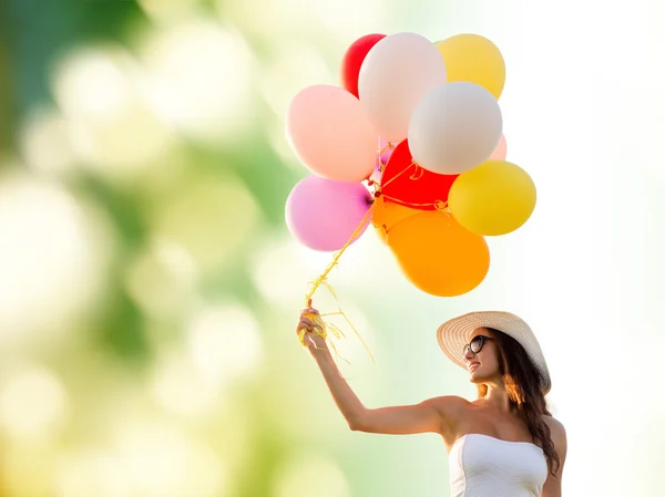 Улыбающаяся молодая женщина в солнечных очках с воздушными шарами — стоковое фото