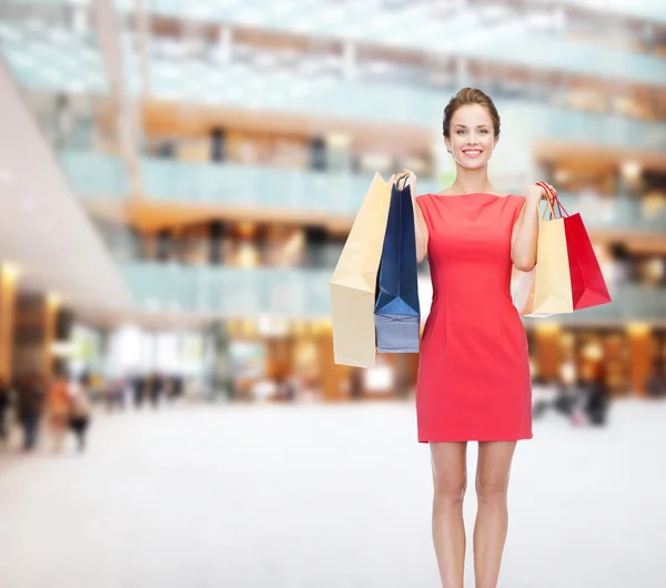 Lächelnde elegante Frau im Kleid mit Einkaufstaschen — Stockfoto