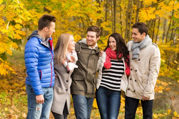 Group of smiling men and women in autumn park — Stock Photo, Image