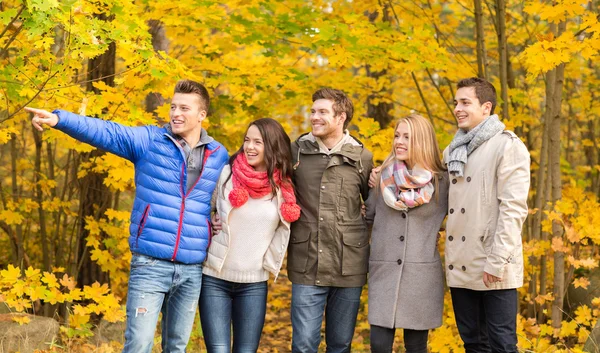 Group of smiling men and women in autumn park — Stock Photo, Image