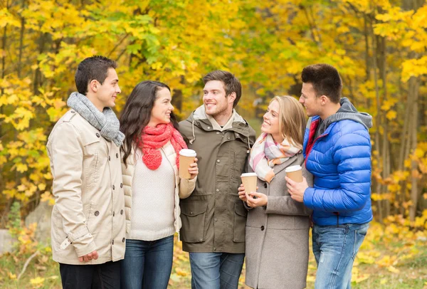 Grupp av leende vän med kaffekoppar i park — Stockfoto