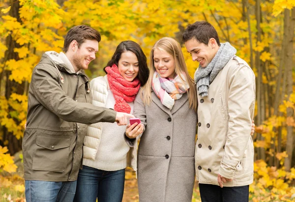 Smiling friends with smartphones in city park — Stock Photo, Image