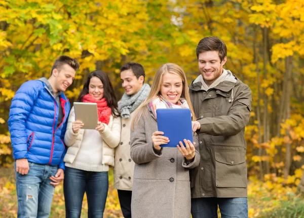 Gruppo di amici sorridenti con tavolette in parco — Foto Stock