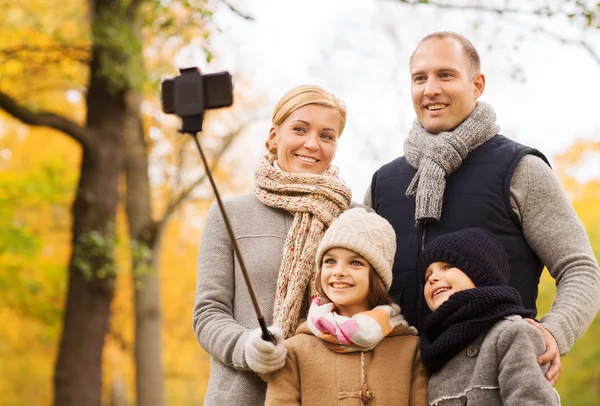 Familia feliz con smartphone y monopod en el parque — Foto de Stock
