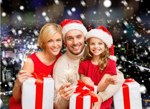 Happy family in santa helper hats with gift boxes — Stock Photo, Image
