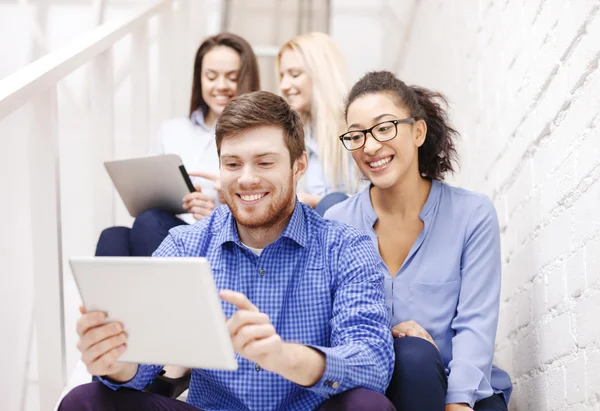 Team with tablet pc computer sitting on staircase — Stock Photo, Image