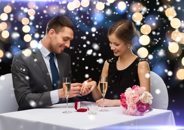 Smiling couple with red gift box at restaurant — Stock Photo, Image