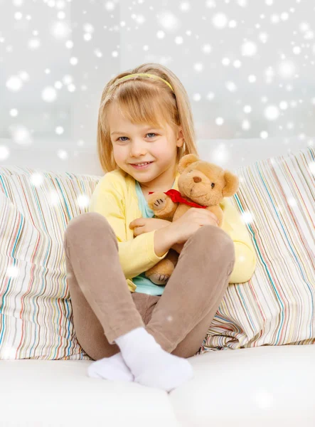 Chica sonriente con oso de peluche sentado en el sofá —  Fotos de Stock
