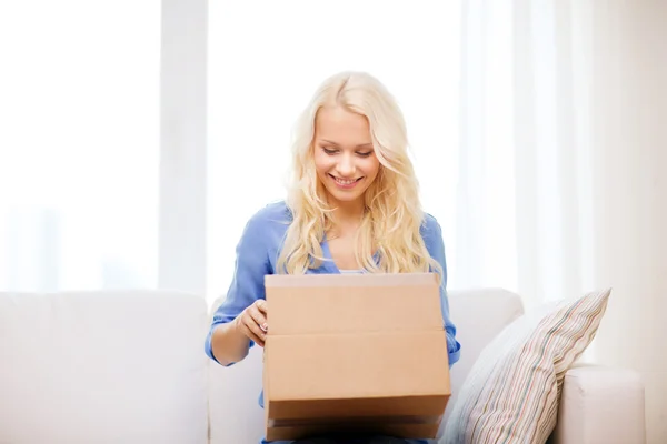 Smiling young woman opening cardboard box — Stock Photo, Image