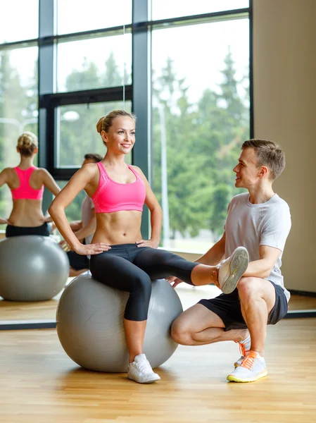 Uomo e donna sorridente con palla da ginnastica in palestra — Foto Stock