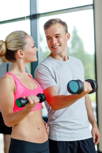 Smiling young woman with personal trainer in gym Stock Image