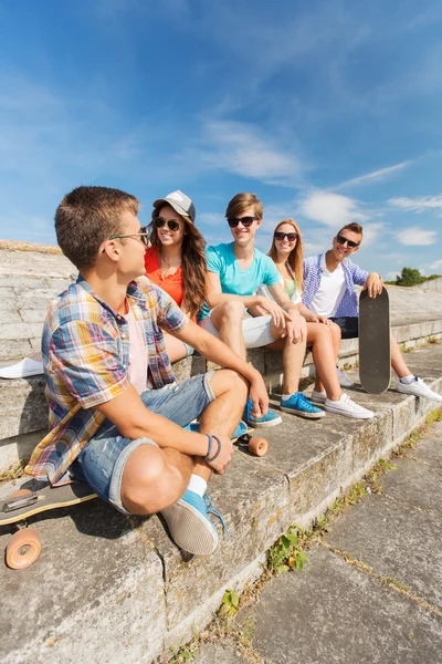 Gruppo di amici sorridenti seduti sulla strada della città — Foto Stock