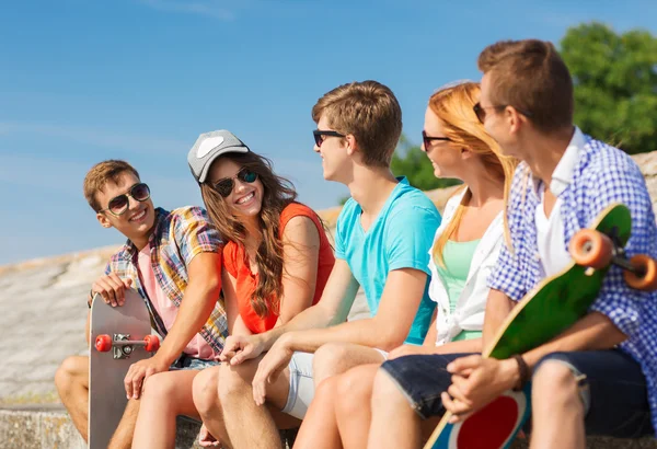 Group of smiling friends sitting on city street — Stock Photo, Image