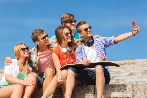 Группа улыбающихся друзей со смартфоном на открытом воздухе — стоковое фото