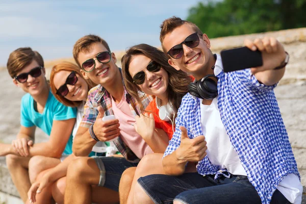 Groupe d'amis souriants avec smartphone en plein air — Photo