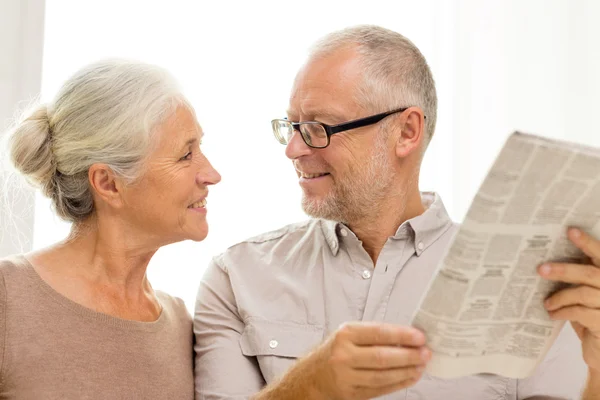 Счастливая пожилая пара читает газету дома — стоковое фото