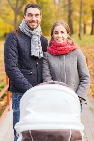 秋の公園でベビーカーと笑顔のカップル — ストック写真