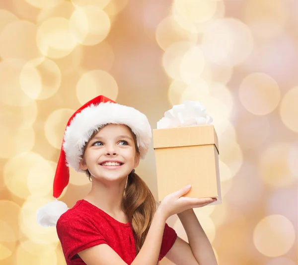 Chica sonriente en sombrero de ayudante de santa con caja de regalo — Foto de Stock