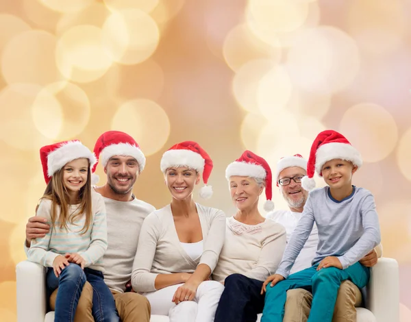 Família feliz em santa helper chapéus sentados no sofá — Fotografia de Stock