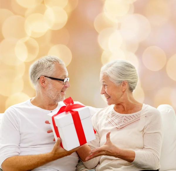 Felice coppia anziana con scatola regalo a casa — Foto Stock
