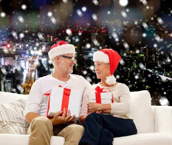 Felice coppia di anziani in cappelli di Babbo Natale con scatole regalo — Foto Stock