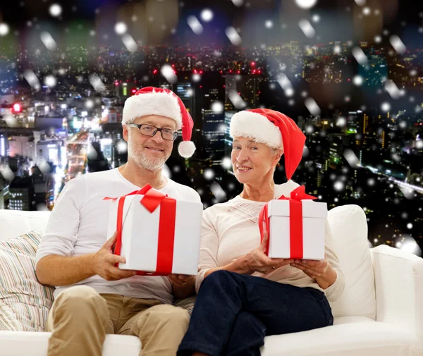 Felice coppia di anziani in cappelli di Babbo Natale con scatole regalo — Foto Stock