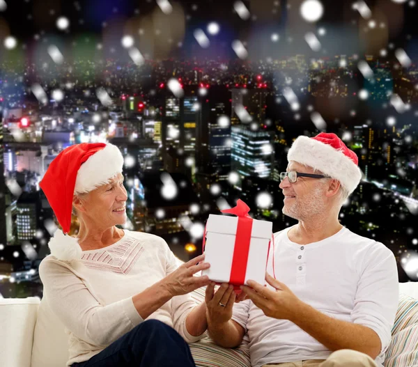 Gelukkig senior koppel in santa hoeden met doos van de gift — Stockfoto