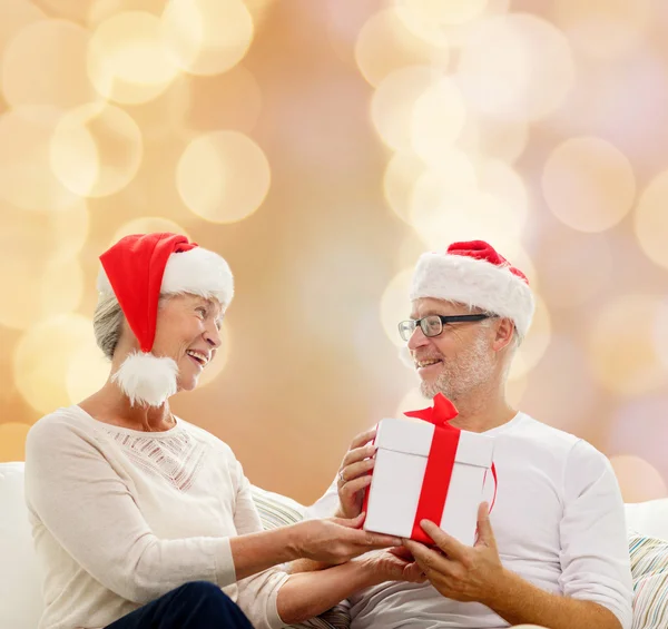 Happy senior couple with gift box at home — Stock Photo, Image