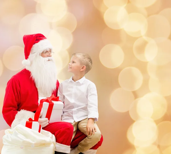 Petit garçon souriant avec santa claus et cadeaux — Photo