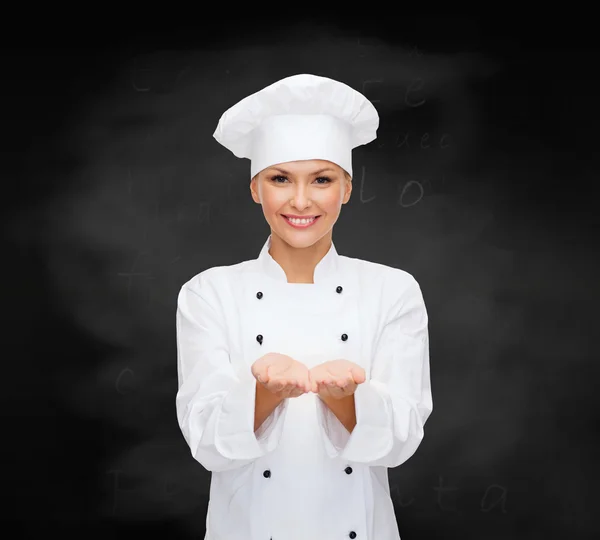 Sorridente chef femminile che tiene qualcosa sulle mani — Foto Stock