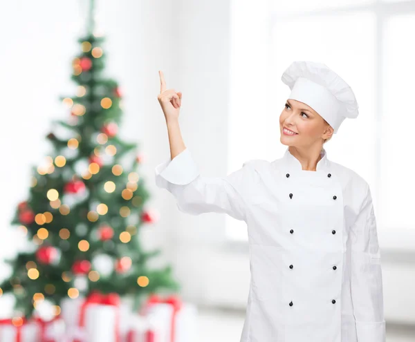 Vrouwelijke chef-kok wijzende vinger om iets te glimlachen — Stockfoto