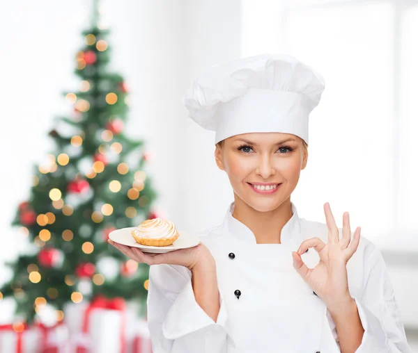 Cuoca sorridente con cupcake sul piatto — Foto Stock