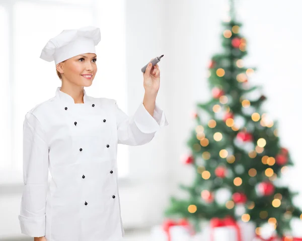 Sorrindo chef feminino escrevendo algo no ar — Fotografia de Stock