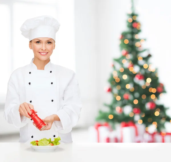 Glimlachend vrouwelijke chef-kok verfraaien plantaardige salade — Stockfoto