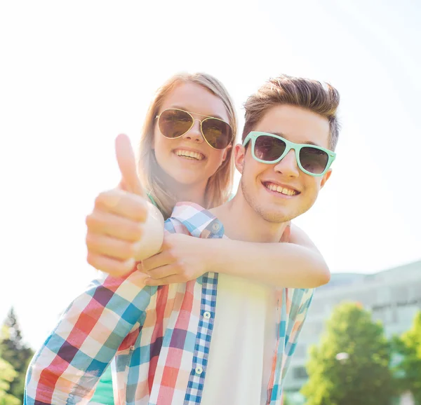 Sonriente pareja divirtiéndose y mostrando pulgares hacia arriba — Foto de Stock