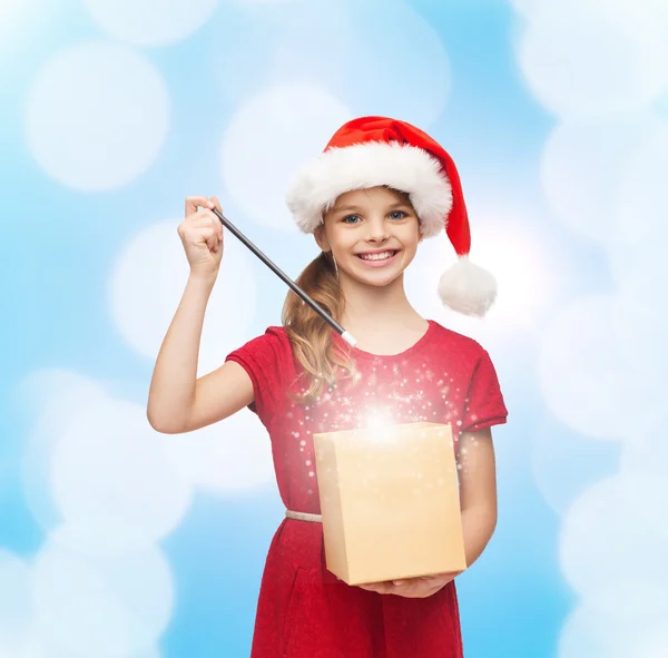 Lächelndes Mädchen mit Weihnachtsmann-Helfermütze mit Geschenkbox Stockbild