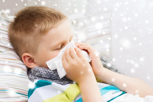 Ziek jongen blazen neus met weefsel thuis — Stockfoto