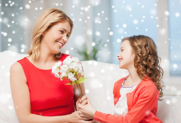 Sonrientes madre e hija con flores en casa —  Fotos de Stock