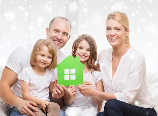 Gelukkige familie met twee kinderen en papier huis thuis — Stockfoto