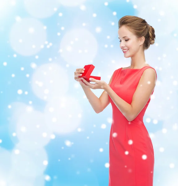 Sorrindo jovem mulher em vestido vermelho com caixa de presente — Fotografia de Stock