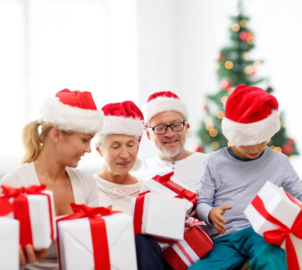 Happy family in santa helper hats with gift boxes — Stock Photo, Image