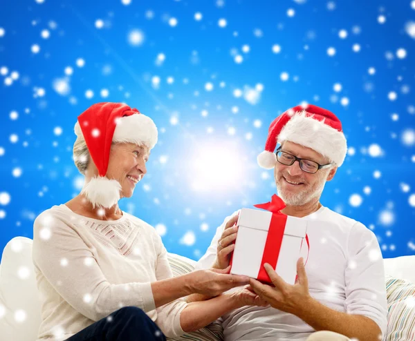Glad äldre par i santa hattar med presentask — Stockfoto