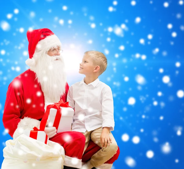 Niño sonriente con santa claus y regalos — Foto de Stock