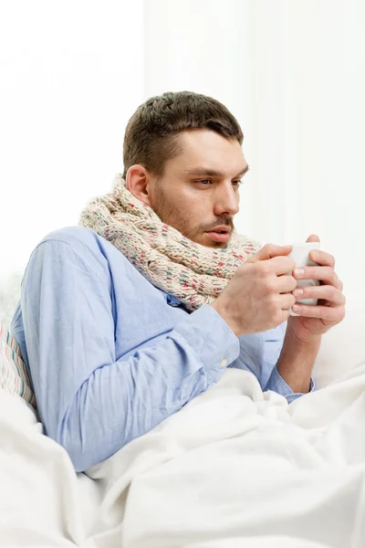 Homme en écharpe tenant tasse avec boisson chaude à la maison — Photo