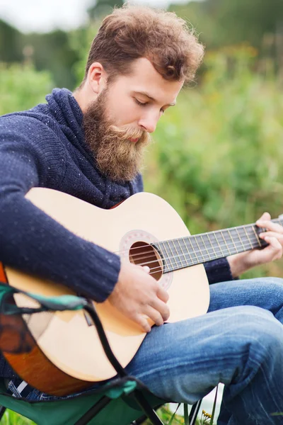 Hombre con barba tocando la guitarra en camping — Foto de Stock