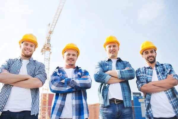 Groep van lachende bouwers in hardhats in openlucht — Stockfoto