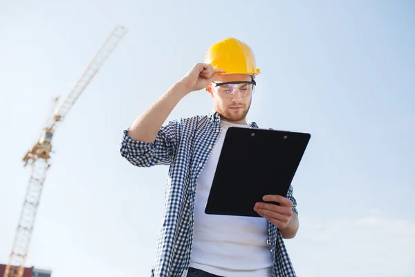Builder in hardhat with clipboard outdoors — Stock Photo, Image
